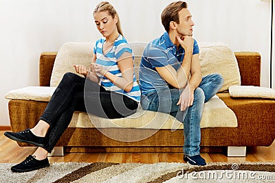 Offended couple sitting back to back on sofa Stock Photo