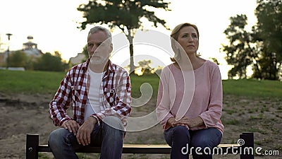 Offended elderly couple sitting on bench and thinking about divorce, relations Stock Photo