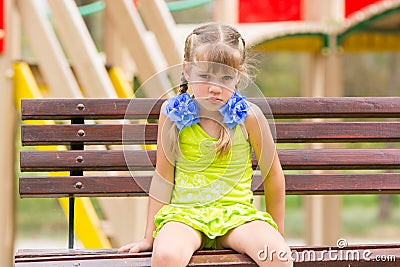 Offended five year old girl sitting on a bench at the playground Stock Photo