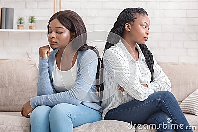 Offended girlfriends sitting back to back, ignoring each other after quarrel Stock Photo