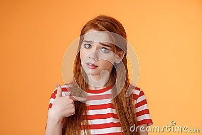 Offended innocent timid redhead girl hurt feelings, hear upsetting accusations, pointing herself frowning, look insulted Stock Photo