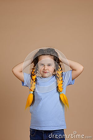 Offended little misbehaving girl holding head with hands looking camera with sullen look having kanekalon braids of Stock Photo