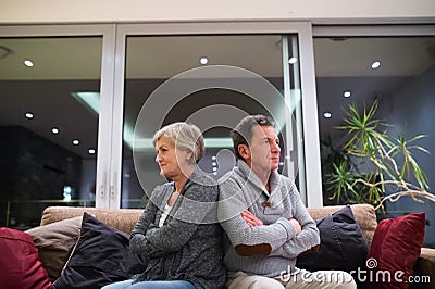 Offended senior couple sitting on a couch with arms crossed Stock Photo