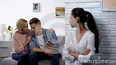 Offended woman secretly watching mother-in-law consoling husband after quarrel Stock Photo