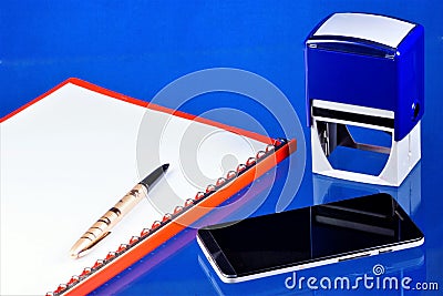 Office accounting desktop, blue background, with the necessary accessories. Folder with documents, smartphone Communicator for Stock Photo