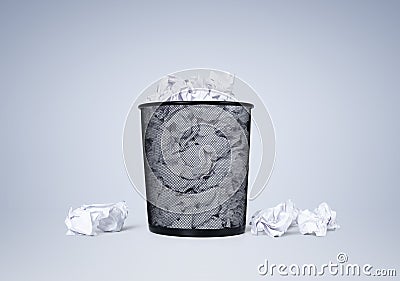 Office black waste bin full of white crumpled paper on blue background. File contains a path to isolation. Stock Photo