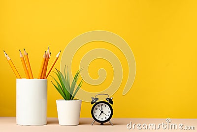 Office cup with pencils and stationery against yellow background Stock Photo