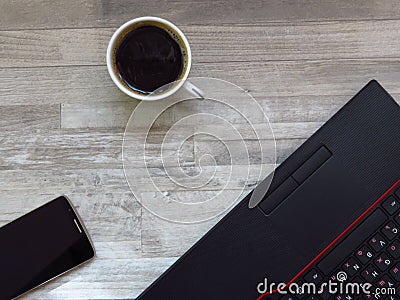 Office desk with black laptop, golden colour mobile phone, a cup of coffee. Business. Success. Coffee break. Top view. Stock Photo