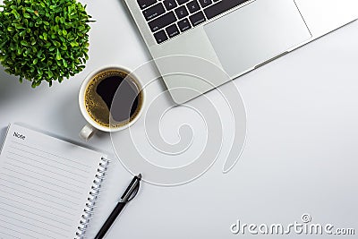Office desk with coffee cup, blank notebook, black pen, laptop computer and plant pot Stock Photo