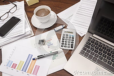 Office desk full with documents, glasses, laptop, and coffee, b Stock Photo