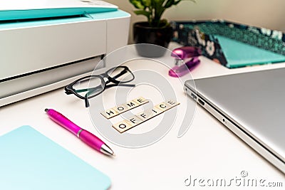Office desk with laptop, printer, supplies and wooden block letters that say Stock Photo