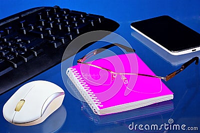 Office Desk with necessary accessories, blue background. On the desktop office notebook for important records, smartphone Stock Photo