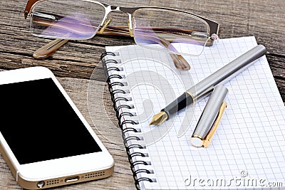 Office desk with notebook, fountain pen, eyeglasses and telephone Stock Photo