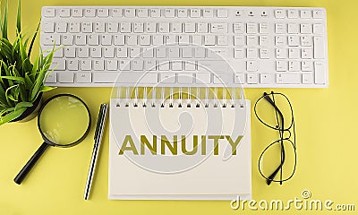 Office desk table Top view with keyboard and notebook text ANNUITY on the yellow background Stock Photo