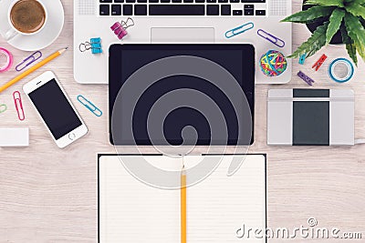 Office desk workplace top view with macbook laptop, ipad tablet, iphone smartphone and open notepad with pencil Stock Photo