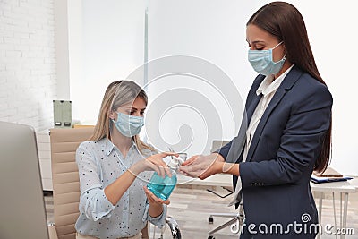 Office employees in respiratory masks applying hand sanitizer Stock Photo