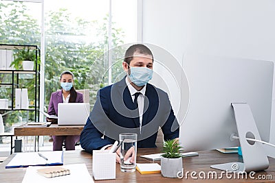 Office employees in respiratory masks at workplace Stock Photo