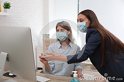 Office employees in respiratory masks at workplace Stock Photo