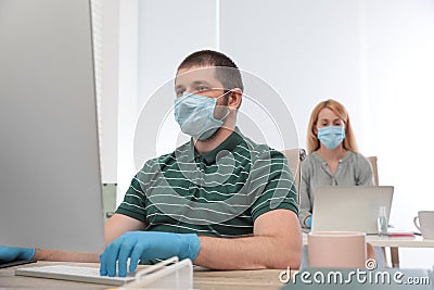 Office employees in respiratory masks at workplace Stock Photo