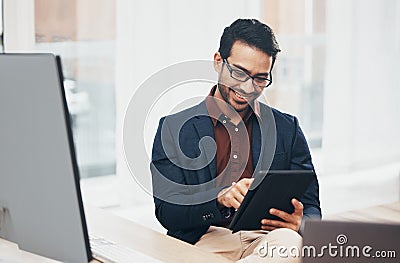 Office, happy Indian man at desk with tablet and computer, reading good news email or successful sales report online Stock Photo