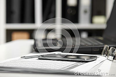 Office interior closeup. Table with laptop, documents, smartphone and eyeglasses Stock Photo