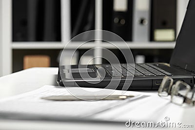 Office interior closeup. Table with laptop, documents, smartphone and eyeglasses Stock Photo