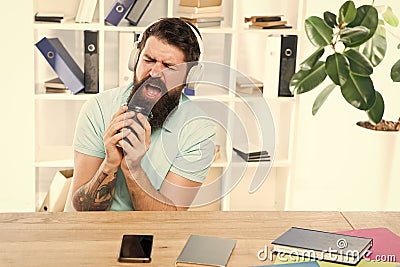 Office life rhythm. Regular office day. Man bearded guy headphones sit office listen music sing song. Worker with coffee Stock Photo