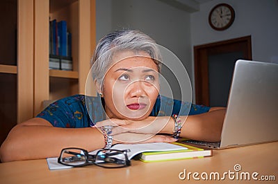 Office lifestyle portrait of sad and depressed middle aged attractive Asian woman working on laptop computer desk stressed and Stock Photo