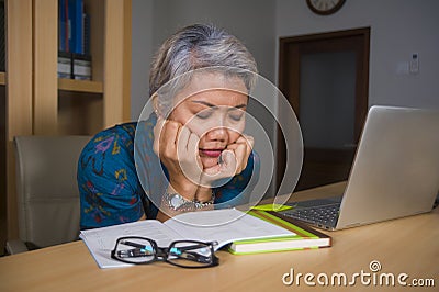 Office lifestyle portrait of sad and depressed middle aged attractive Asian woman working on laptop computer desk stressed and Stock Photo