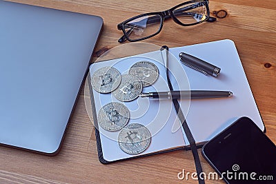 Office Portable work area Silver coins Bitcoin laptop Mobile phone Glasses, notebook and writing pen. Concept of Bitcoin Cryptocur Stock Photo
