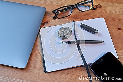 Office Portable work area Silver coins Bitcoin laptop Mobile phone Glasses, notebook and writing pen. Concept of Bitcoin Cryptocur Stock Photo