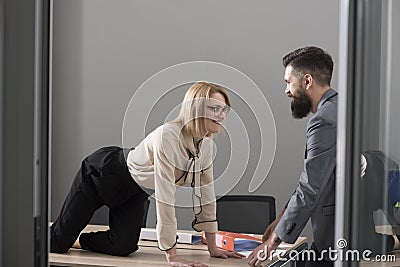 Office romance concept. secretary seduce boss in office. Businesswoman on desktop look at bearded businessman. Man Stock Photo