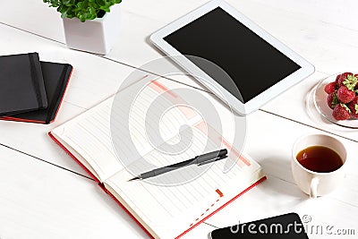 Office table desk with set of supplies, white blank notepad, cup, pen, tablet, flower on white background. Top view Stock Photo