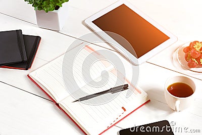 Office table desk with set of supplies, white blank notepad, cup, pen, tablet, flower on white background. Top view Stock Photo