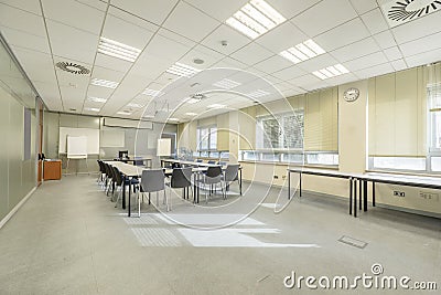 Office with a training room with a U-shaped table filled with chairs overlooking a projection screen, technical ceilings and a Stock Photo