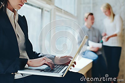 Office work process. Woman with laptop and team meeting in loft Stock Photo