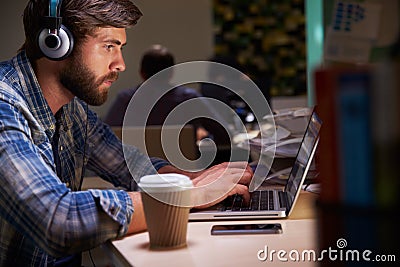 Office Worker With Coffee At Desk Working Late On Laptop Stock Photo