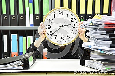 Office worker holding a clock, Working overtime and lot of work Stock Photo