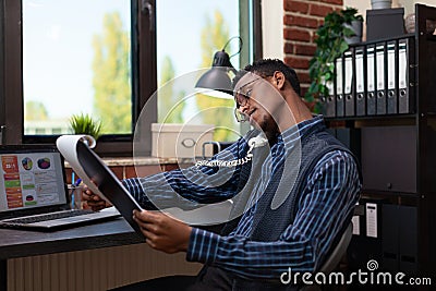 Office worker holding phone reciever on shoulder with tilted head looking at clipboard Stock Photo