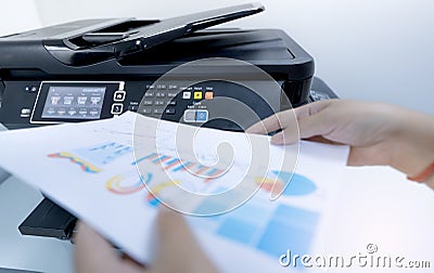 Office worker prints paper on multifunction laser printer. Copy, print, scan, and fax machine in office. Document and paper work. Stock Photo