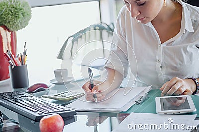 Office worker at workplace. Girl writing on paper. Stock Photo