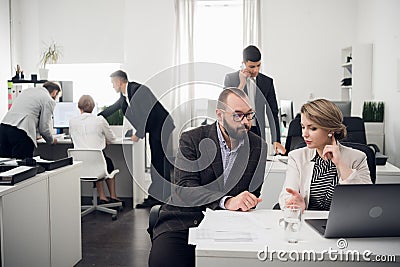 Office workers talk about something, man talks on phone, other three work at a table on backgorund Stock Photo