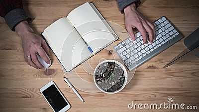 Office workplace with Hands. Laptop, daily planner, glasses and phone on a wooden table. Top View Stock Photo
