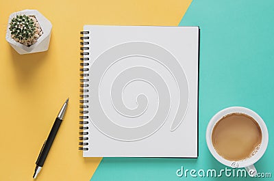 Office workplace minimal concept. Blank notebook with cup of coffee, cactus, pencil on yellow and blue background. Stock Photo