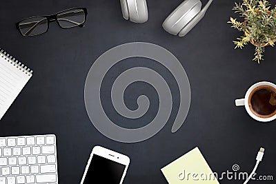 Office workspace with computer keyboard, smart phone, cup of coffee, headphones, glasses, notepad, plant Stock Photo