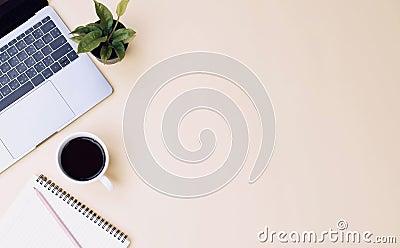 office workspace yellow desk table with laptop, coffee, mobile, notebook, plant Stock Photo