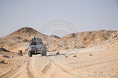 Offroad car in desert landscape bahariya egypt. Low point of view. Car tracks in the sand and volcano hills in the background. Stock Photo