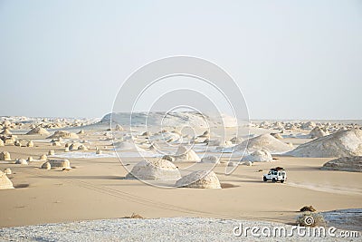 Offroad car in desert landscape white desert egypt. Low point of view. Car tracks in the sand and volcano hills in the background. Stock Photo