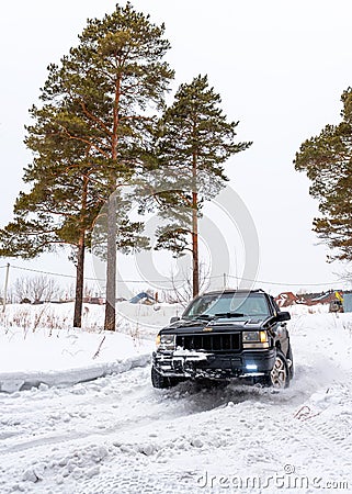 Offroad SUV `Jeep Grand Cherokee` 4x4 with off- road training rides in winter on snow in the forest among pines with a female. Editorial Stock Photo