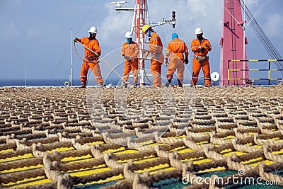 A team of riggers or roughnecks installing landing net on a helipad of a construction work barge Editorial Stock Photo